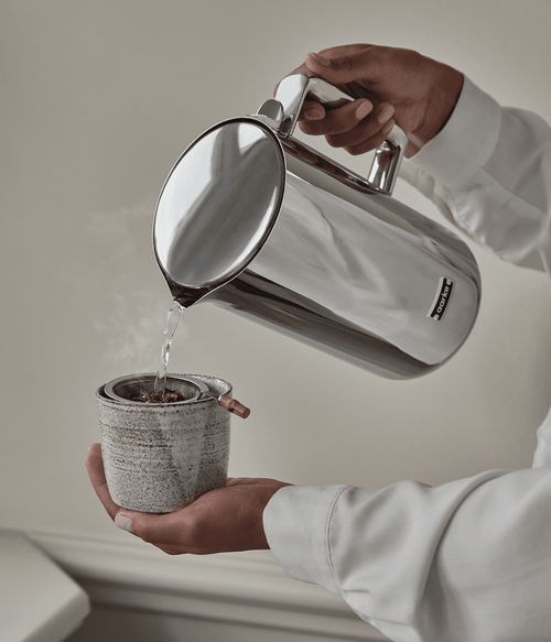 Person using the Aarke kettle stainless steel and pouring water into a tea cup. 