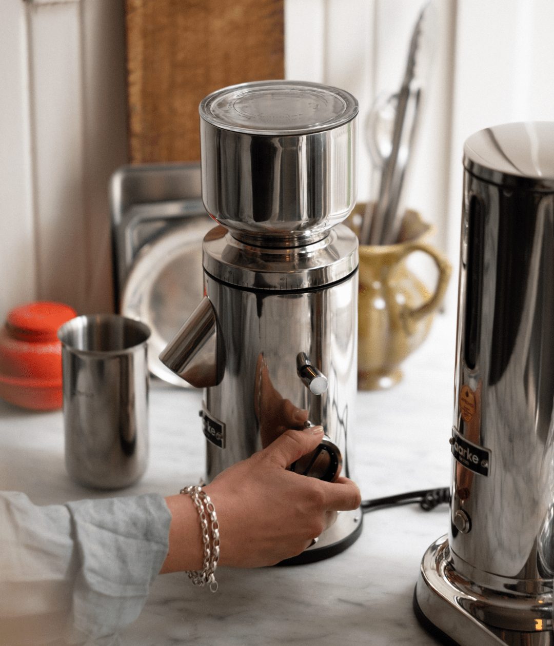 Close-up of a hand adjusting the grind setting on the Aarke stainless steel coffee grinder.