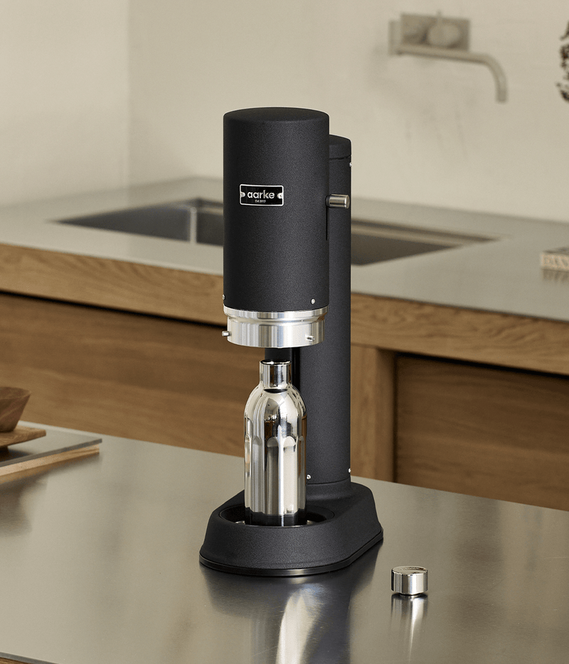 Aarke Carbonator Pro in Matte Black with the Stainless Steel Bottle Small inserted, set on a stainless steel kitchen counter.