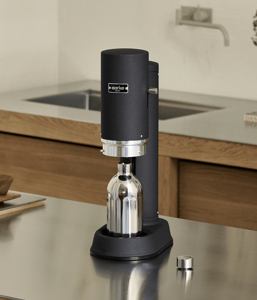 Aarke Carbonator Pro in Matte Black with the Stainless Steel Bottle inserted, set on a stainless steel kitchen counter.