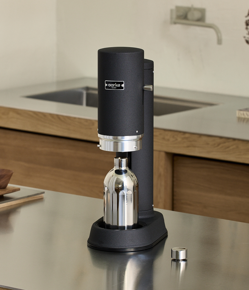 Aarke Carbonator Pro in Matte Black with the Stainless Steel Bottle inserted, set on a stainless steel kitchen counter.
