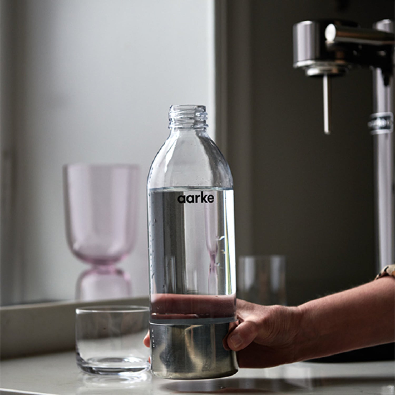 A person sets a full Aarke PET Bottle onto a counter.