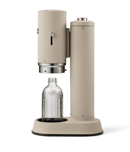 Side view of Carbonator Pro Sand, shown with a glass bottle inside the open chamber, partially filled with carbonated water.