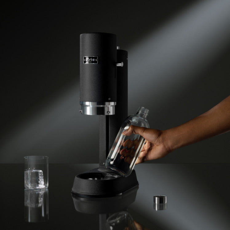 A person places a bottle into the Aarke Carbonator Pro in Matte Black.