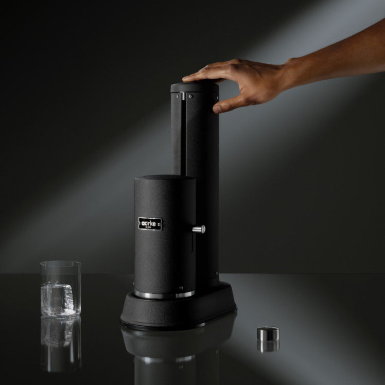 A person pressing the button to carbonate using the Aarke Carbonator Pro in Matte Black.