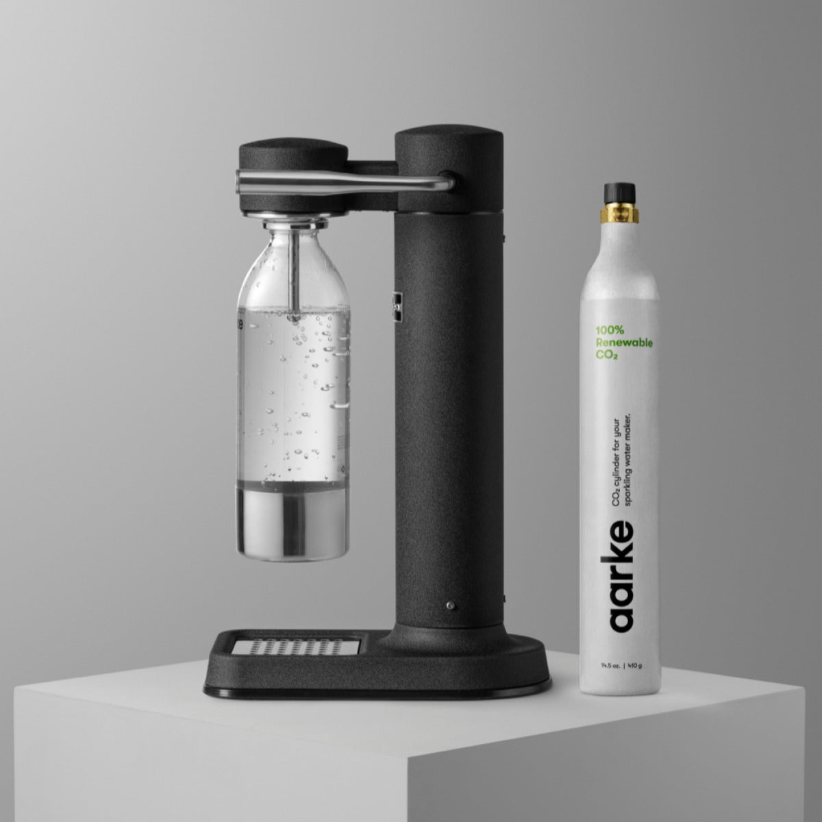 The Aarke Carbonator 3 in Matte Black pictured with a PET bottle attached beside an Aarke CO2 Cylinder.