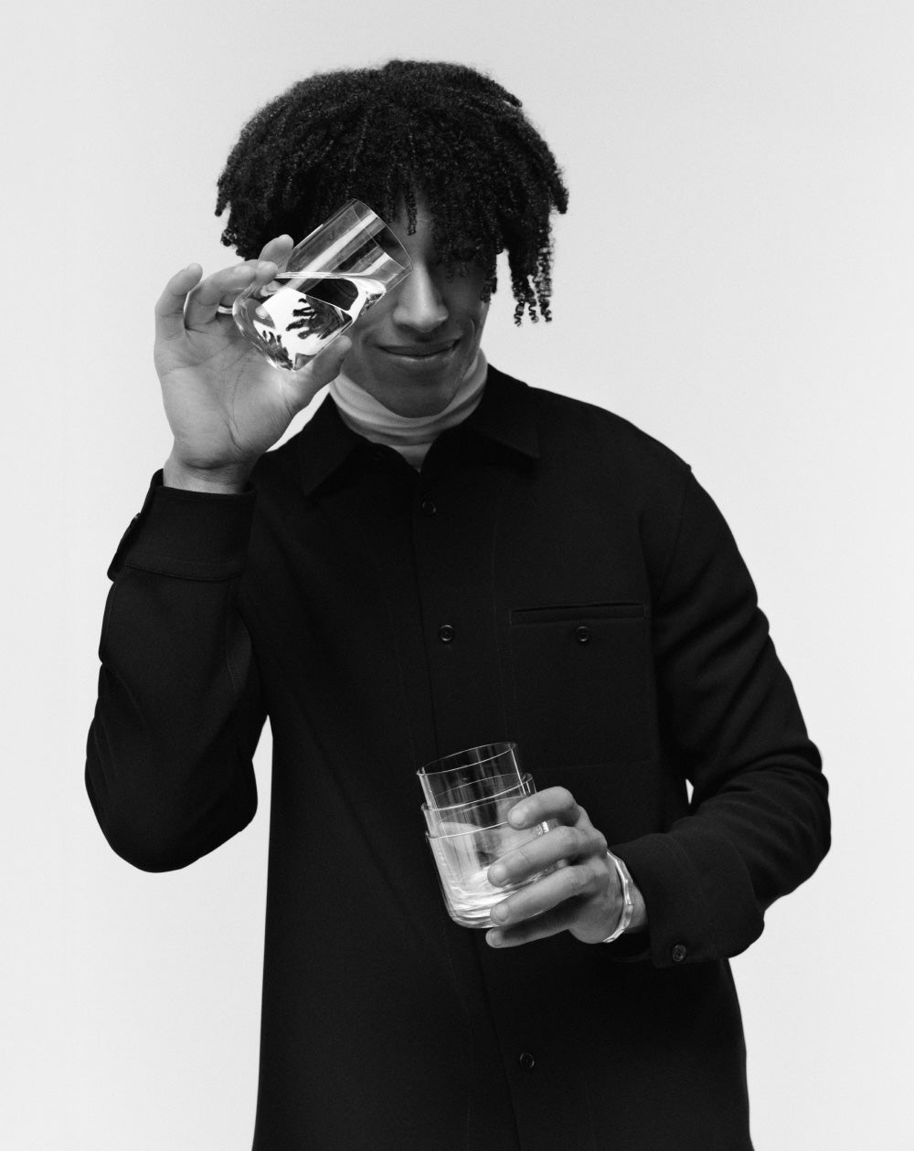 Person holding a crystal aarke glass with a design on a plain background