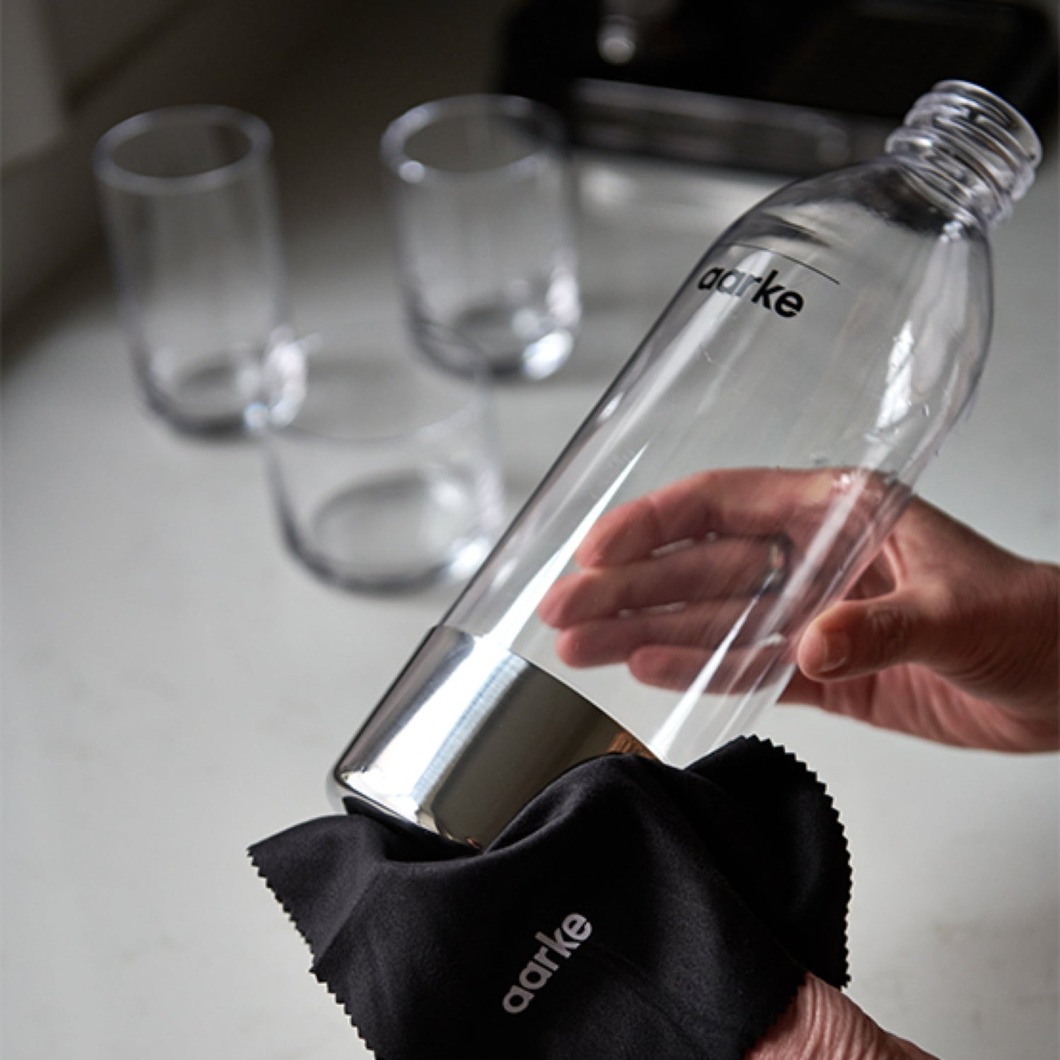 A person wipes the Aarke PET Bottle clean with a cloth.