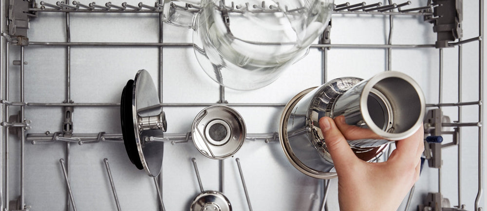 A person puts the pieces of the Aarke Water Filter Pitcher into a dishwasher.