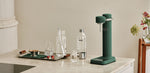 Aarke Carbonator 3 sparkling water maker in Heritage Green with Aarke BPA-free PET bottle and freshly carbonated sparkling water.