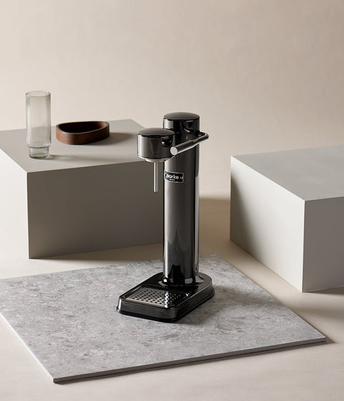 Aarke Carbonator 3 in Black Chrome displayed on a stone surface with minimalist decor in a studio setting.