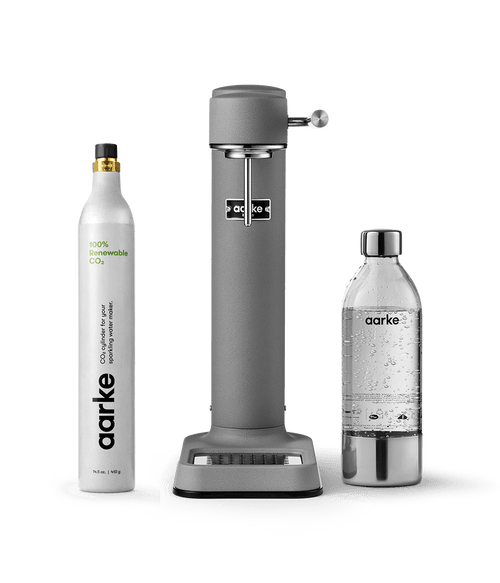 Aarke Carbonator 3 in Matte grey displayed with a 100% renewable CO2 cylinder next to a filled PET water bottle.