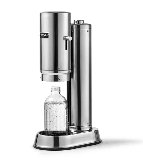 Aarke Carbonator Pro in Steel, shown in use with a clear bottle inside the open chamber, partially filled with carbonated water.