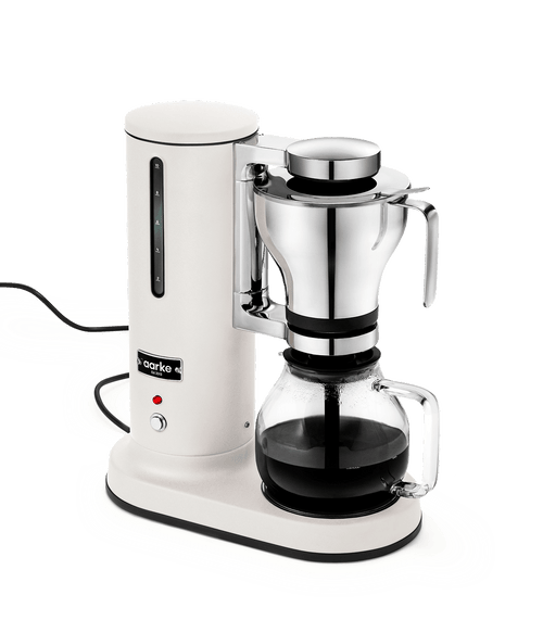 Aarke Coffee Maker in Matte White with a stainless steel brew basket and class carafe with freshly brewed coffee.