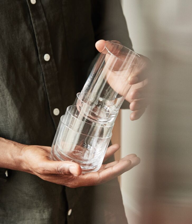 Person holding Aarke Nesting Glasses set, removing top glass to show stackable design.