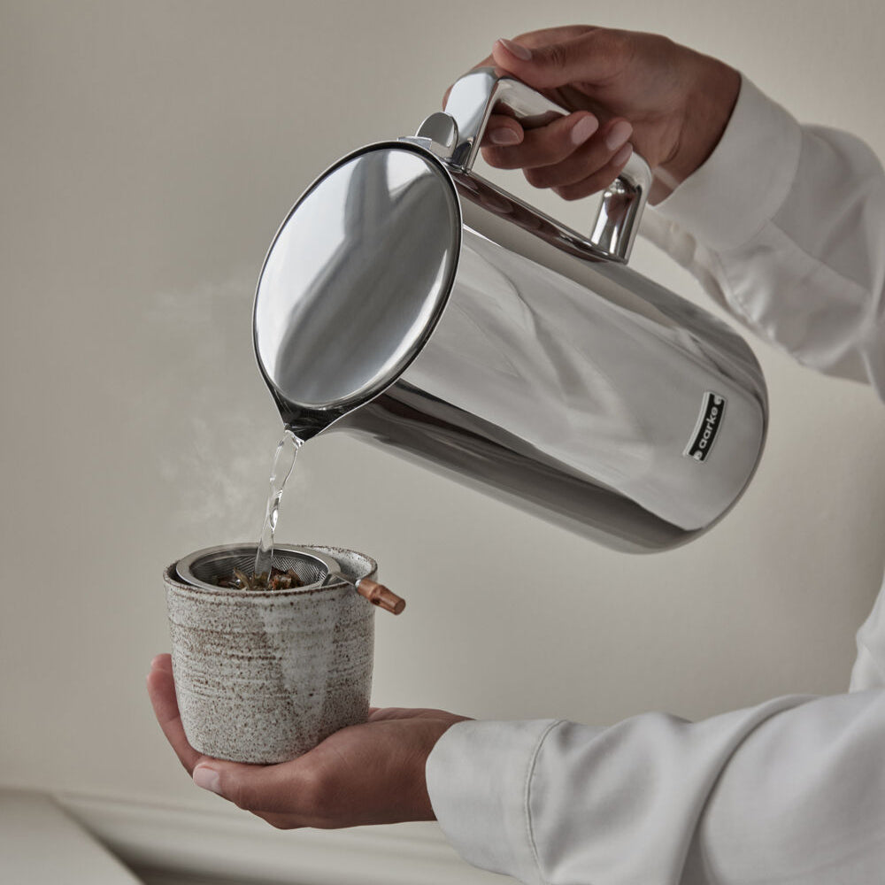 A person pouring hot water into a mug from the Aarke Kettle.