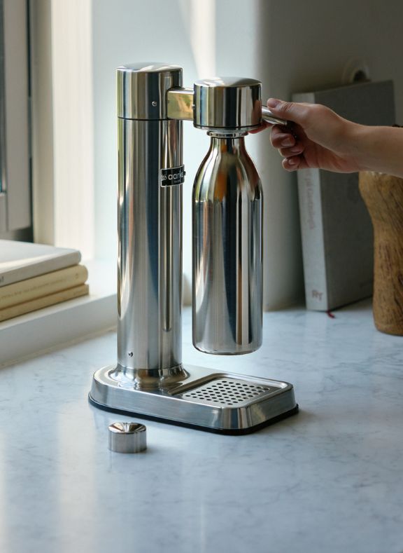 Silver kitchen appliance with a bottle on a marble countertop