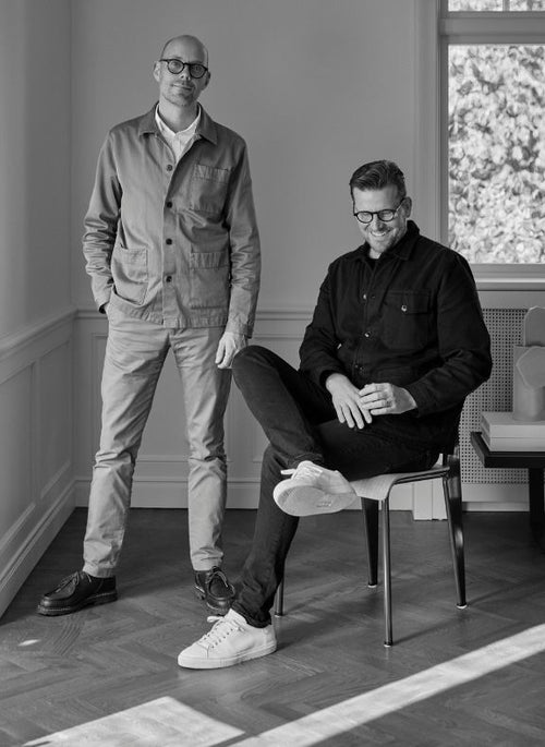 Two men in a room with a window in the background