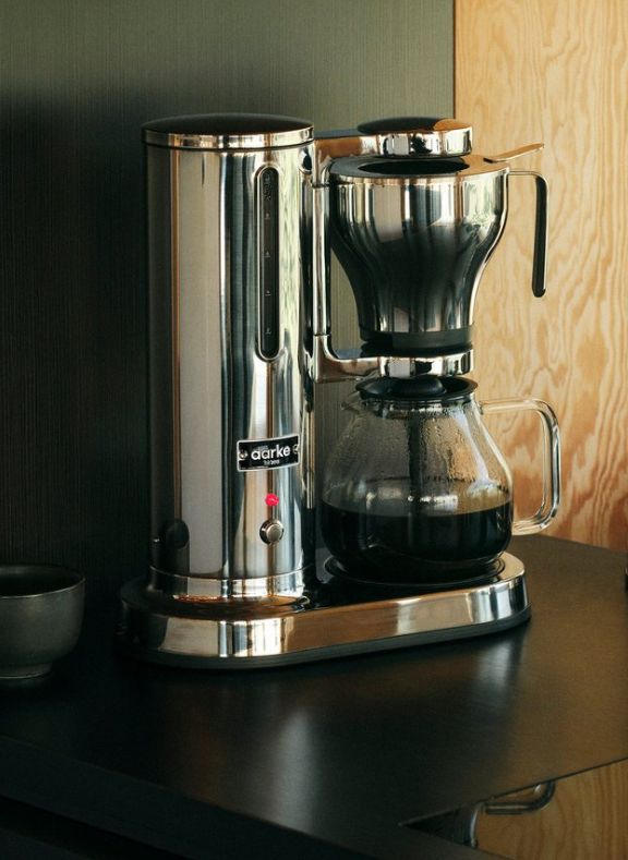 Aarke Stainless steel coffee maker with glass carafe on a wooden surface