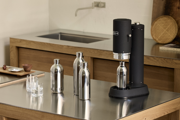 Aarke Carbonator Pro Matte Black with three stainless steel bottles on a modern kitchen countertop.