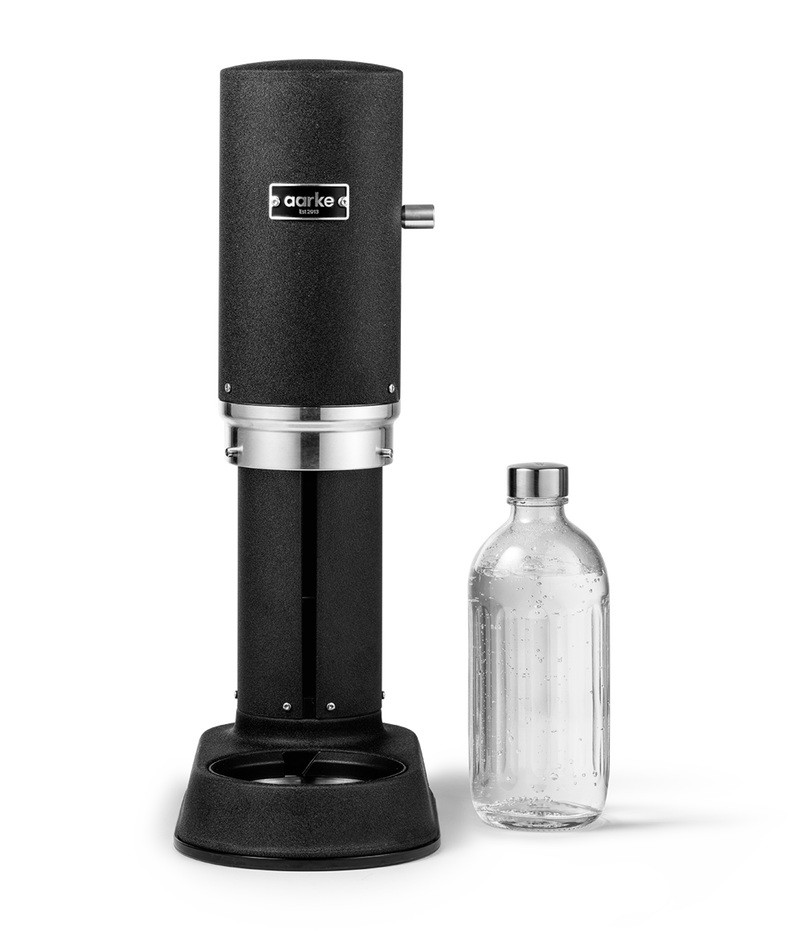Aarke Carbonator Pro in Matte Black. Front view with chamber open and Glass Bottle sitting beside.